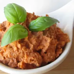 Pyszna pasta z białej fasoli, doprawiona ziołami i udekorowana listkami bazylii, podana w białej miseczce.