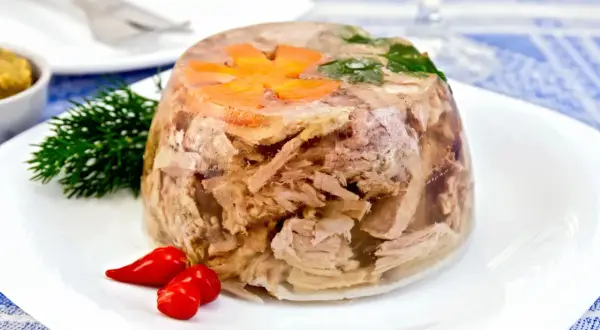 Pyszna galareta wieprzowa z marchewką i koperkiem, podana z papryczkami chili. Czas jej tężeje to kwestia cierpliwości.