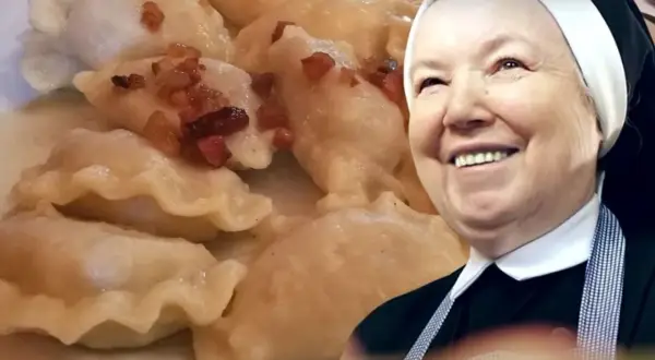 Uśmiechnięta zakonnica obok talerza pysznych pierogów z kaszą gryczaną i skwarkami.