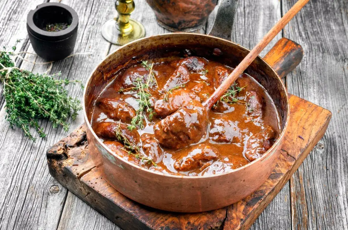 Gulasz wieprzowy w miedzianym rondlu, z gałązkami tymianku. Idealny przykład, ile dusic wieprzowine, by była miękka.