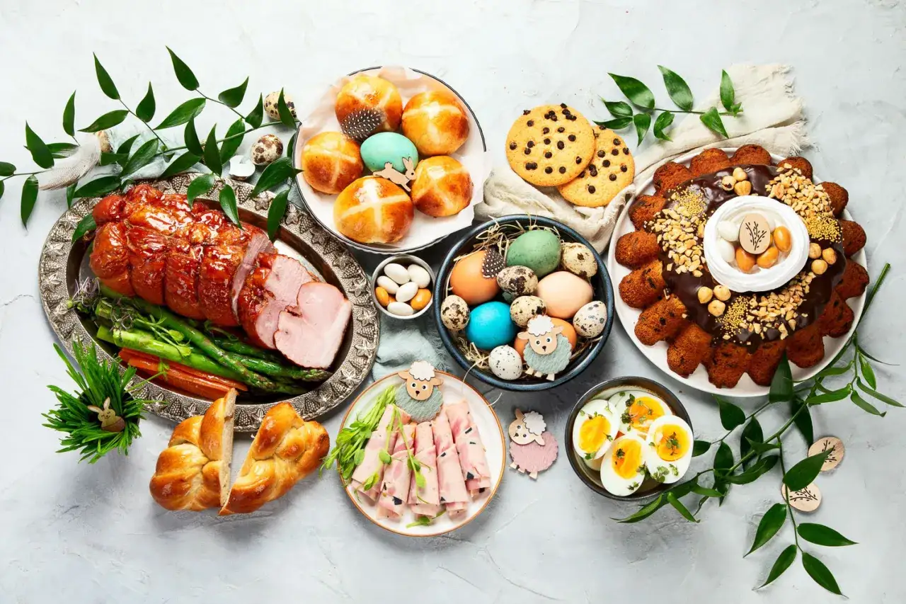 Wielkanocny stół pełen smakołyków: pieczona szynka, pascha, jajka, babeczki i słodkości. Idealne menu na Wielkanoc.